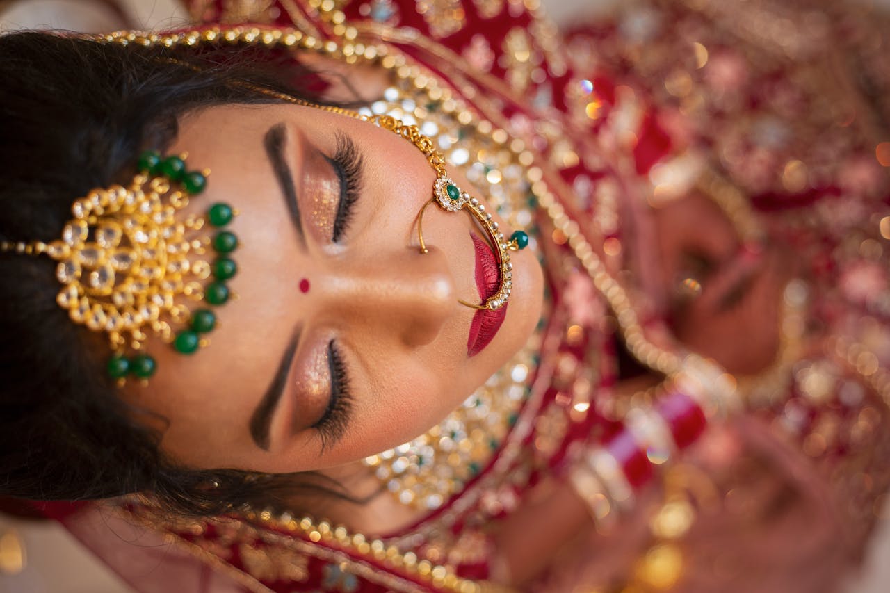 get-in-touch Stunning Indian bride in traditional attire and bridal jewelry, eyes closed.