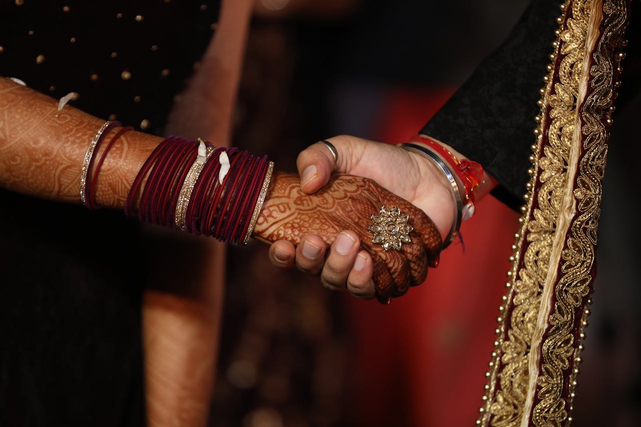 services-bg Close-up of a couple's hands with henna and bangles, symbolizing unity in an Indian wedding ceremony.
